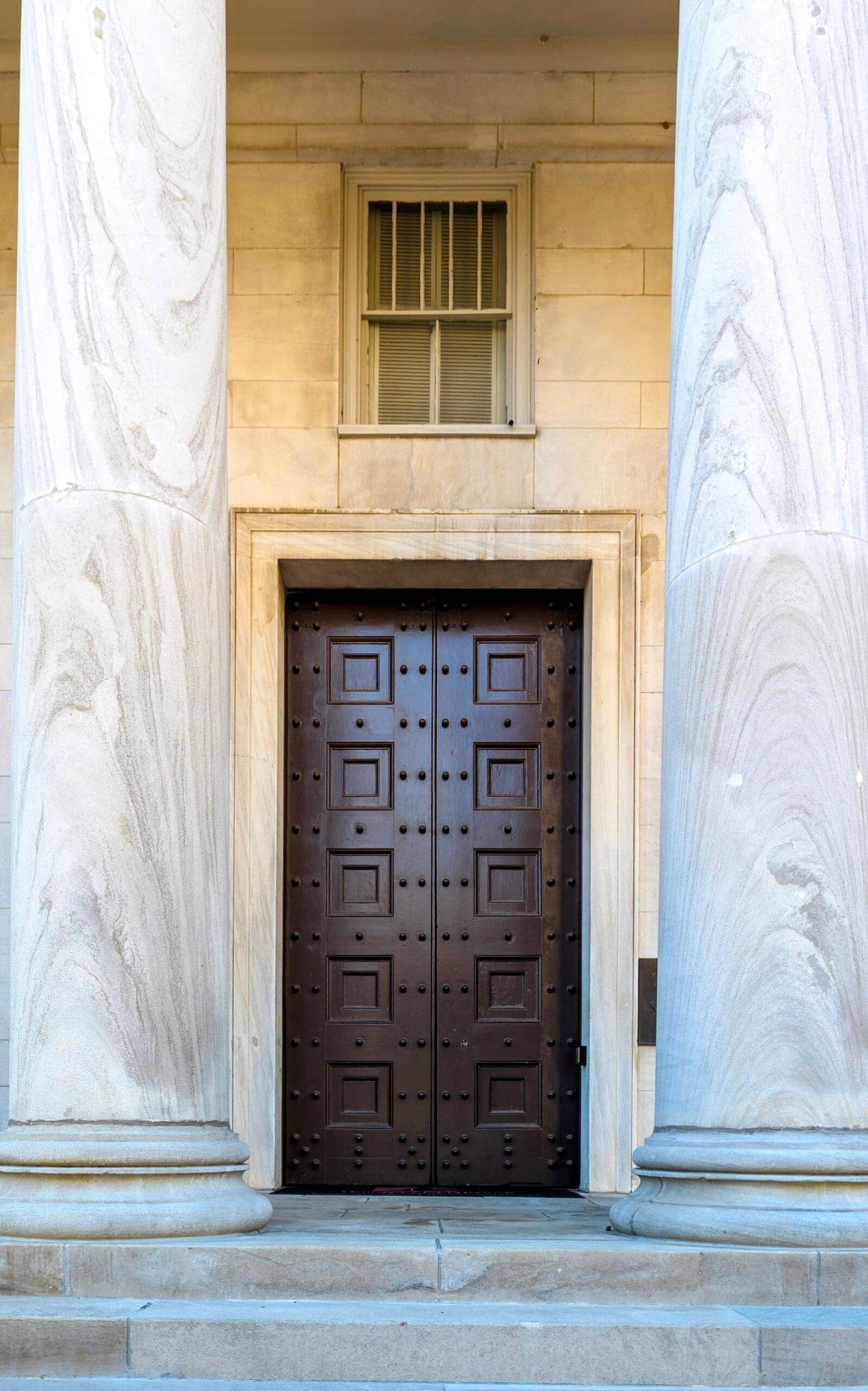 Stone columns and heavy wooden doors at a courthouse entrance, the kind of building where criminal cases from Altoona, Pennsylvania are heard